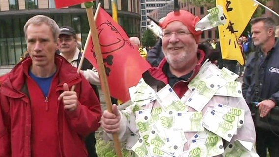 Ein mit Euroscheinen verkleideter Mann auf einer Demonstration.  