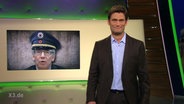 Christian Ehring neben einem Bild von de Maiziere als mit Polizistenmütze.  