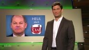 Christian Ehring steht neben einem Bild von Olaf Scholz.  