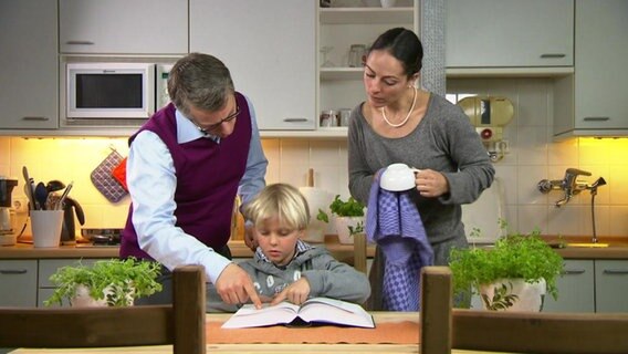 Mutter und Vater helfen einem Jungen bei seinen Hausaufgaben.  