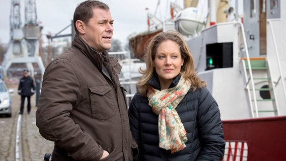 Aufregung im Lübecker Hafen. Die Besatzung eines Feuerwehrschiffs hat einen Toten aus dem Wasser gezogen. Finn (Sven Martinek, l.) und Elke (Tessa Mittelstaedt, r.) wollen sich ein Bild vor Ort machen. © NDR/ARD/Georges Pauly 
