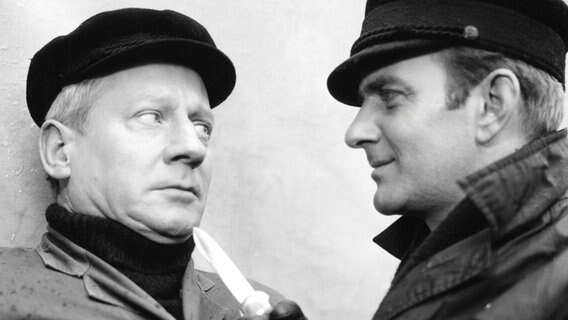 Robert Schneider und der Speditionsfahrer Lambeck vertauschen im Morgengrauen auf dem Hamburger Flughafen fünf Kisten "Spezialkameras für Beirut". Streifenfahrer Hartmann, der seine Braut zum Flugfeld bringt, entdeckt in einem abgestellten Wagen den niedergestochenen Speditionsangestellten Brügge. Er alamiert Kommissar Koldehoff. Beim Umladen in München plazt eine Kiste der Firma Schneider. Rostiges Blech rollt heraus. Die Schlinge um den Erpresser und Versicherungsbetrüger Schneider zieht sich zu. Robert Schneider und der Speditionsfahrer Lambeck vertauschen im Morgengrauen auf dem Hamburger Flughafen fünf Kisten "Spezialkameras für Beirut". Streifenfahrer Hartmann, der seine Braut zum Flugfeld bringt, entdeckt in einem abgestellten Wagen den niedergestochenen Speditionsangestellten Brügge. Er alamiert Kommissar Koldehoff. Beim Umladen in München plazt eine Kiste der Firma Schneider. Rostiges Blech rollt heraus. Die Schlinge um den Erpresser und Versicherungsbetrüger Schneider zieht sich zu. © NDR/Döltz, honorarfrei