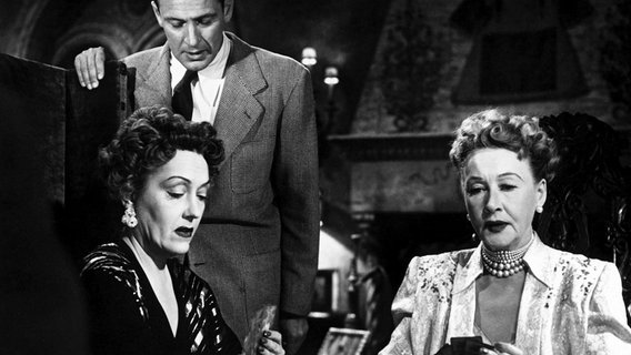 Die alternde Diva Norma Desmond (Gloria Swanson, links) trifft gelegentlich die gefürchtete Klatschkolumnistin Hedda Hopper (von ihr selbst gespielt). Joe (William Holden) möchte dieser skrupellosen Welt Hollywoods entkommen, schafft es aber zunächst nicht, weil er die Armut fürchtet. © NDR/BR/Telepool 