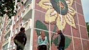 August 1992: Mehrere hundert rechtsextreme Randalierer greifen die Zentrale Aufnahmestelle für Asylbewerber und ein Wohnheim für vietnamesische Vertragsarbeiter im sogenannten Sonnenblumenhaus mit Molotowcocktails an – unter dem Applaus von bis zu 3.000 Zuschauern. NDR Reporter Bernd Kalauch wohnte damals selbst in Lichtenhagen, für Clemens Paulsen war es der erste Einsatz als Außenreporter. © NDR 