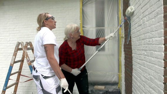 Eine Frau streicht die Rotklinker-Fassade ihres Hauses. © NDR/nonfictionplanet/Marco Peschmann 