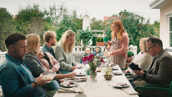 Szenenbild aus der schwedischen Serie "Everyone but us": Viele Personen sitzen an einem gedeckten Tisch im Garten. Szenenbild aus der schwedischen Serie "Everyone but us": Viele Personen sitzen an einem gedeckten Tisch im Garten. © Warner Bros International