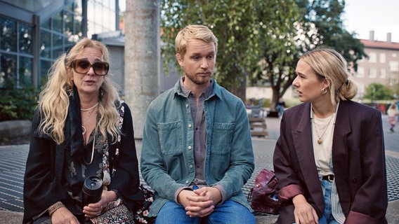 Szenenbild aus der schwedischen Serie "Everyone but us": Drei Personen sitzen auf einer Mauer. Szenenbild aus der schwedischen Serie "Everyone but us": Drei Personen sitzen auf einer Mauer. © Warner Bros International