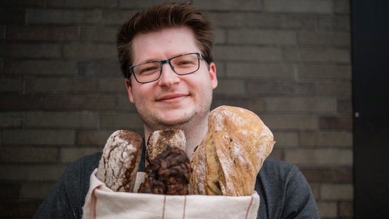 Ein Mann hält eine offene "Tüte", aus der Brote gucken, vor dem Bauch. © NDR/Dörte Haupt 
