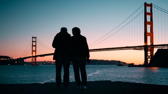 Hoepker und Kruchen am Ziel ihrer Reise vor der Golden Gate Bridge in San Francisco während der Abenddämmerung. Hoepker und Kruchen am Ziel ihrer Reise vor der Golden Gate Bridge in San Francisco während der Abenddämmerung. © NDR/GRANVISTA Media