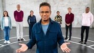 Wie egoistisch bist du? Moderator Michail Paweletz und die sechs Teilnehmenden in einer ehemaligen Lagerhalle in Hamburg. (v.l.n.r.: Mitra Kassai, Jörg von Grass, Julia Breckheimer, Priyanka Balamohan, Johannes Kolb, Rene Mang) © NDR/Stefan Mühlenhoff 