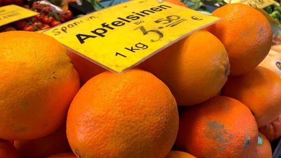 Apfelsinen mit einem Preisschild in der Auslage eines Supermarkts. © NDR/stennerfilm 
