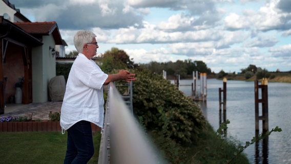 Ein Frau steht an ein Geländer gelehnt und schaut aufs Wasser. © NDR 