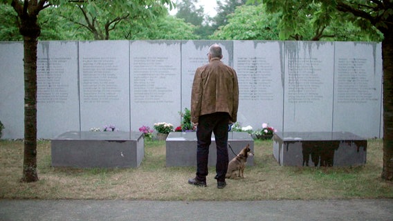 Ein Mann steht vor einer Gedenktafel. © NDR 