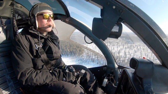 Ossi Lukkarila riskiert sein Leben für den Strom: Weil schneeverhangene Bäume auf die Stromleitungen fallen können, sägt er sie ab - mit dem Helikopter. © NDR/Hamburg Enterprises/NRK/SVT/YLE 