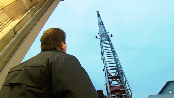 Thomas Breitkopf beobachtet jeden Schritt der Feuerwehranwärter*innen auf der dreißig Meter hohen Drehleiter. Thomas Breitkopf beobachtet jeden Schritt der Feuerwehranwärter*innen auf der dreißig Meter hohen Drehleiter. © NDR/FILMBLICK