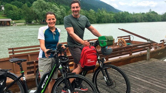 Die Kärtnerin Anna Pacher (l) begleitet Moderator Marco Schreyl auf dem E-Bike durch ihr Heimatland Kärnten. © NDR/WDR/Caro Wagner 