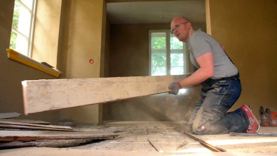 Bauherr Daniel Hoherz beim Entfernen der alten Dielen im Wohnzimmer der Alten Apotheke in Nusse. © NDR/Ulrike Schede 