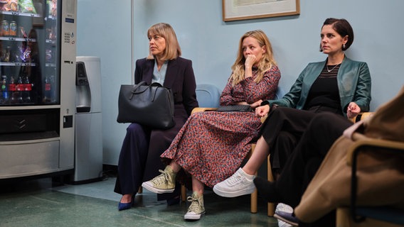 Szenenbild aus der Serie "The Split - Beziehungsstatus ungeklärt": Drei Frauen sitzen nebeneinander in einem Wartezimmer. © Sister Pictures Foto: Tereza Cervenova