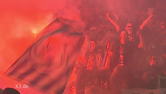 Hooligans im Stadion mit brennenden Bengalos  
