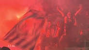Hooligans im Stadion mit brennenden Bengalos  