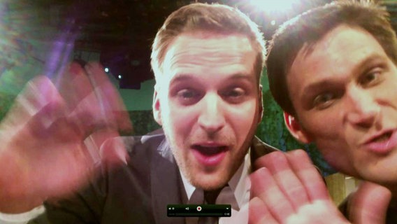 Klaas Butenschön und Christian Ehring schauen in eine Webcam.  