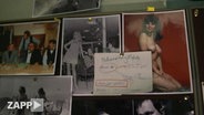 Eine Fotowand mit journalistischen Fotografien, aber auch Nacktbildern von Frauen.  