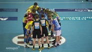 Die Spieler der Mecklenburger Stiere Schwerin und des HSV Handball bilden einen Kreis.  