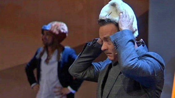 Tom Hanks setzt sich den Hut eines Katzenkostüms auf.  
