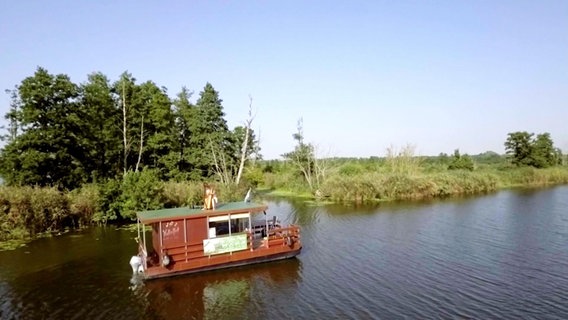 Ein Hausboot auf einem See der Mecklenburgischen Seenplatte.  