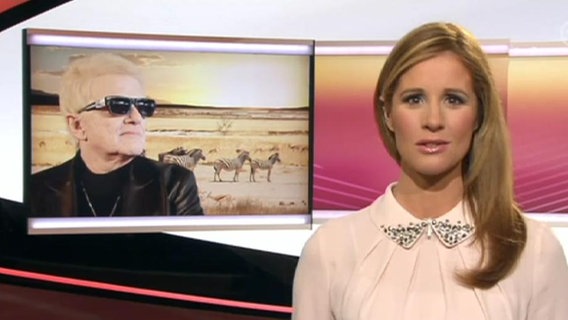 Eine Moderatorin vor einem Bild von Heino.  