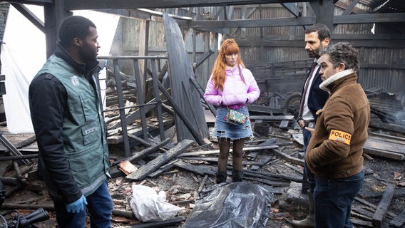Szenenbild aus der französischen Serie "HIP: Ermittlerin mit Mords-IQ": Vier Personen stehen in einer abgebrannten Scheune. © François Roelants Foto: François Roelants