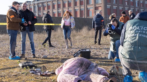 Szenenbild aus der französischen Serie "HIP: Ermittlerin mit Mords-IQ": Viele Personen sind an einem Tatort. Eine Person liegt am Boden. © NDR/Philippe Le Roux/Itineraire Prod/TF1 Foto: Philippe Le Roux/Itineraire Prod/TF1