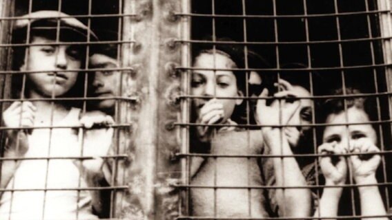 Archivaufnahme: Jüdische Kinder stehen hinter Gittern. © Screenshot NDR 