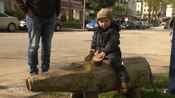 Ein kleines Kind sitzt auf einem Schwein aus Holz.  