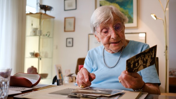 Seniorin Helga Rode schaut sich ein Schwarzweiß-Foto an. © NDR Foto: André Bacher