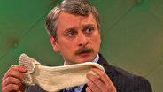 Johannes Schlüter hält eine weiße Socke in den Händen.  