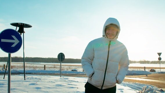 René steht in Winterjacke an einer Straße, die Landschaft ist von Schnee bedeckt. © NDR Foto: Christoph Heymann
