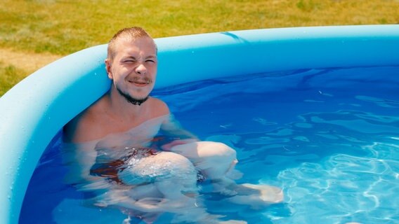 René sitzt in einem aufblasbaren Pool im Garten. © NDR Foto: Christoph Heymann