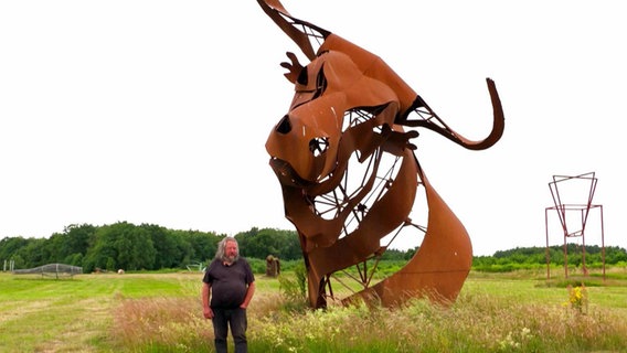 Ein Mann steht neben einer riesigen Stier-Skulptur. © NDR/Kulturjournal 