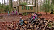 Vor dem Bauwagen eines Waldkindergartens bei Plön spielen Kinder.  