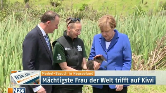 Angela Merkel streichelt einen Kiwi.  