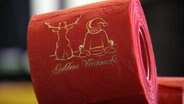 Eine Rolle rotes Klopapier mit goldener Verzierung.  