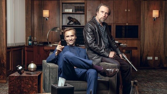 Szenenbild aus der Impro-Serie "Kranitz - Bei Trennung Geld zurück": Zwei Männer sitzen bzw. lehnen an einem Sessel. © ARD Degeto/NDR/Thomas Leidig 