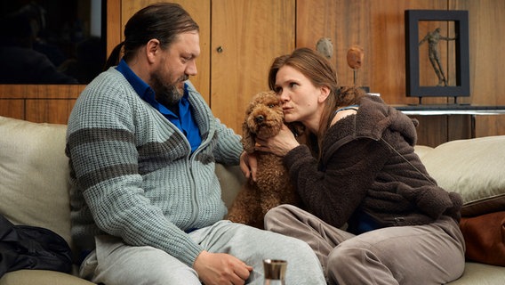 Szenenbild aus der Impro-Serie "Kranitz - Bei Trennung Geld zurück": Ein Paar sitz mit einem Hund auf einem Sofa. © ARD Degeto/NDR/Thomas Leidig 