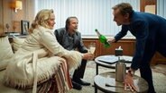 Szenenbild aus der Impro-Serie "Kranitz - Bei Trennung Geld zurück": Ein Mann schenkt einen Paar Sekt ein. © ARD Degeto/NDR/Thomas Leidig 