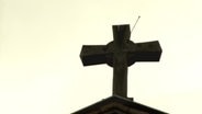Ein Kreuz auf einem Kirchendach.  