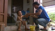 Der vietnamesische Junge Long Thanh wird von seinem Vater gewaschen.  