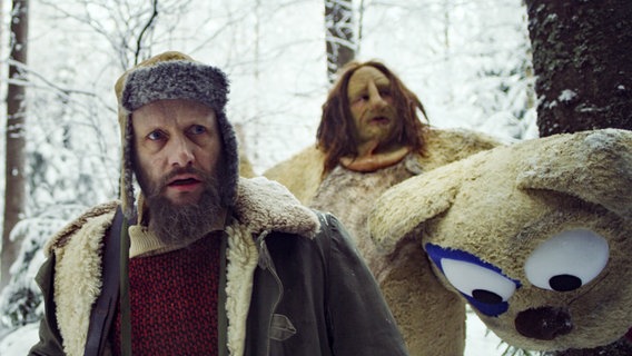 Ein Mann und ein Troll sind im verschneiten Wald unterwegs. © NDR/Viafilm AS 