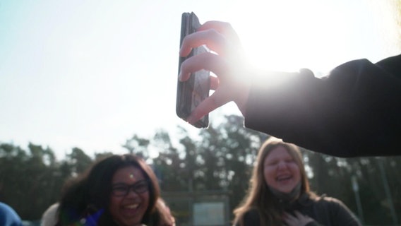 Schülerinnen der Waldschule Hatten schauen auf ein Handy. © NDR 