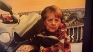 Ein Plakat zeigt Angela Merkel auf einem Motorrad  